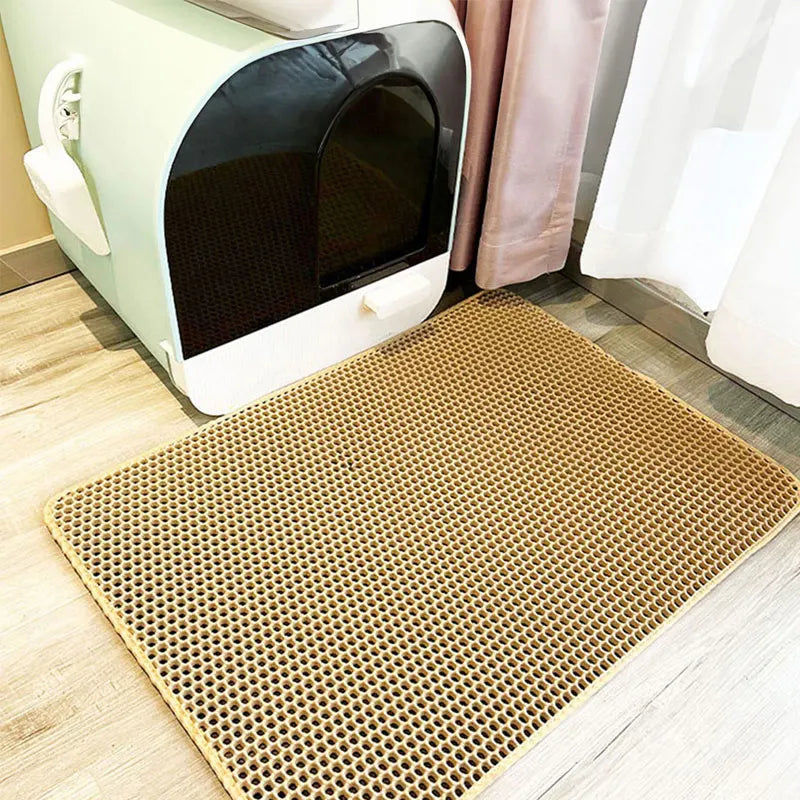 Tapis beige alvéolé posé au sol devant une maison de toilette pour chat vert d'eau, parquet clair
