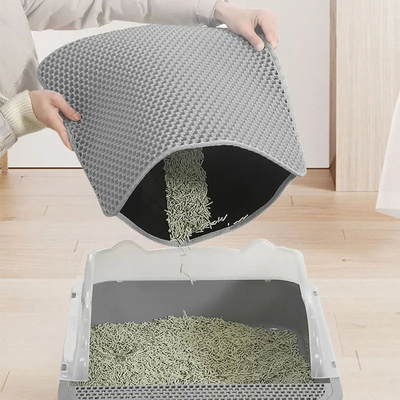 Main soulevant un tapis gris pour verser dans le bac les granulés végétaux récupérés sous la surface