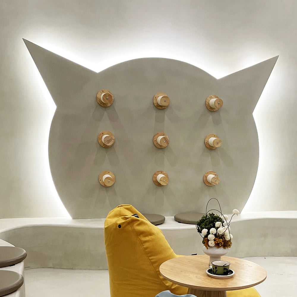 Neuf plots muraux en bois alignés en grille sur un mur en forme de tête de chat, salon avec pouf jaune