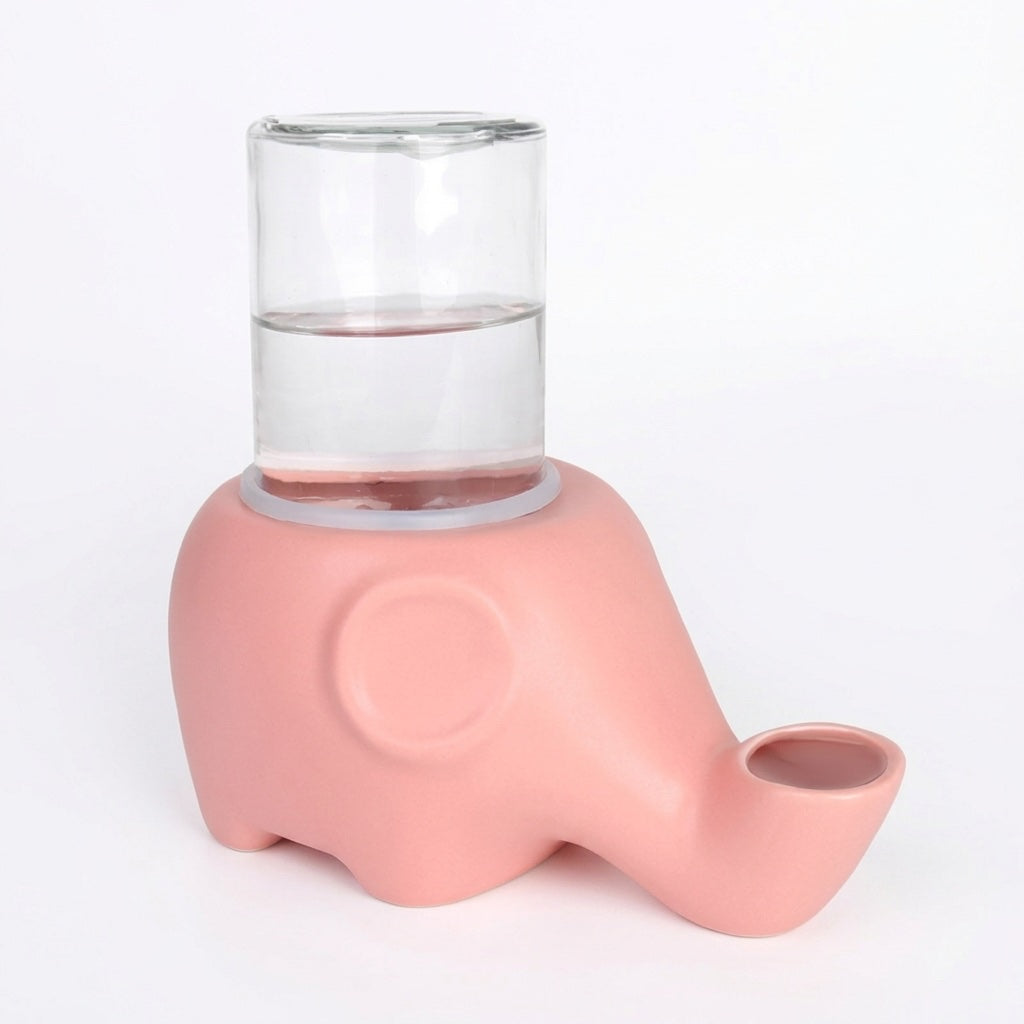 Distributeur d'eau pour chat rose en céramique mate, bouteille en verre à moitié remplie posée sur le dos de l'éléphant