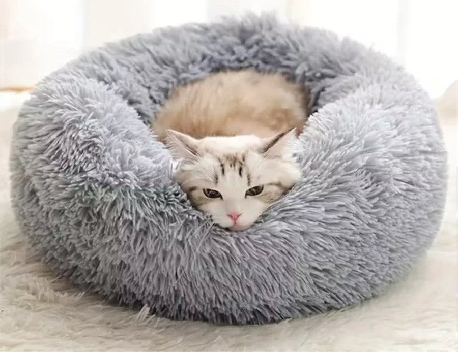 Cat lying in the gray faux fur donut cat bed